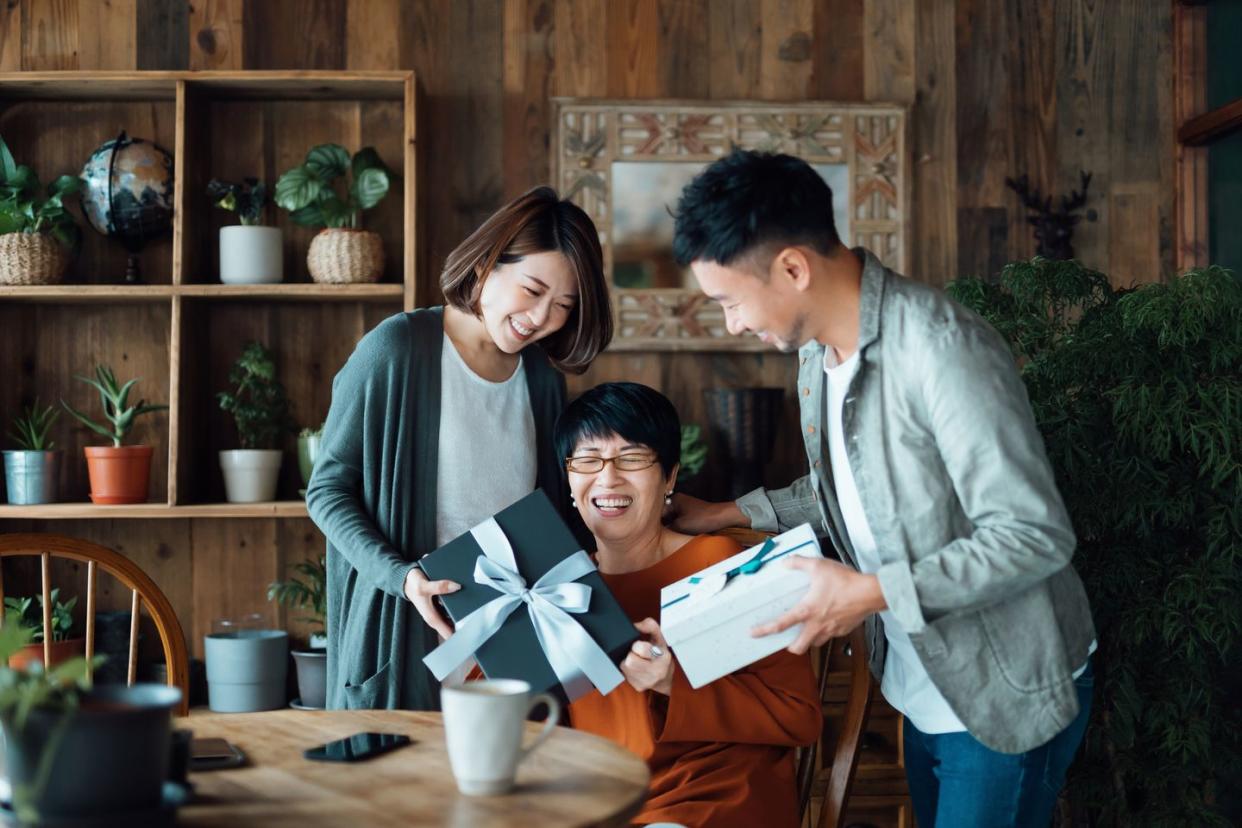 a senior mother receiving presents from her daughter and son at home