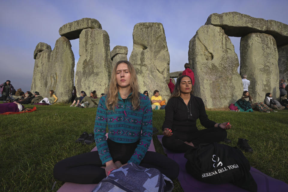 Revelers meditate next to stones at sunrise as thousands gather at the ancient stone circle Stonehenge to celebrate the Summer Solstice, the longest day of the year, near Salisbury, England, Wednesday, June 21, 2023. (AP Photo/Kin Cheung)
