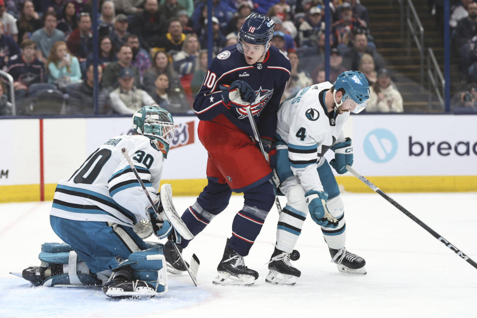 San Jose Sharks goalie Magnus Chrona (30) stops a shot in front of Columbus Blue Jackets forward Dmitri Voronkov (10) and Sharks defenseman Kyle Burroughs (4) during the second period of an NHL hockey game in Columbus, Ohio, Saturday, March 16, 2024. (AP Photo/Paul Vernon)