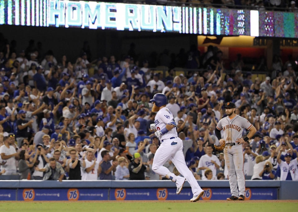 Los Angeles Dodgers' Justin Turner, left, heads to third as he passes by San Francisco Giants third baseman Evan Longoria watches after Turner hit a solo home run during the fifth inning of a baseball game Monday, Aug. 13, 2018, in Los Angeles. (AP Photo/Mark J. Terrill)