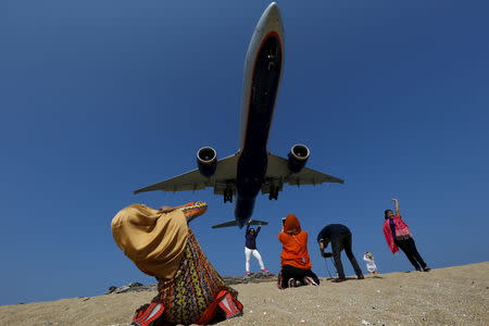 Tourists take pictures at Mai Khao Beach, as a plane approaches the Phuket International Airport in Phuket, Thailand March 17, 2016. REUTERS/Athit Perawongmetha/Files