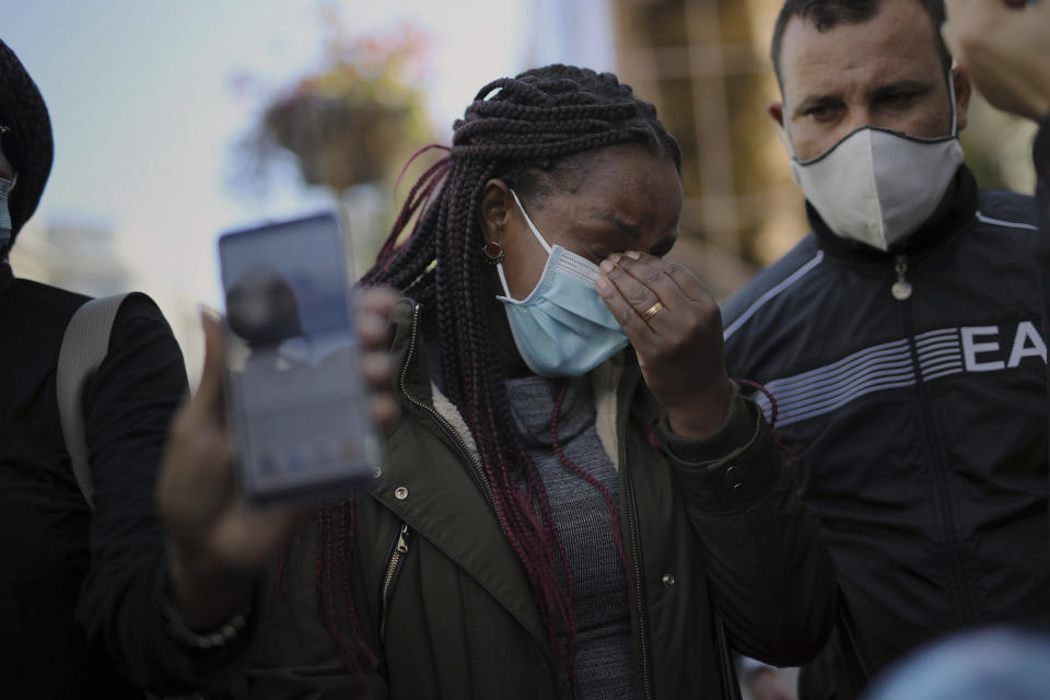 Sylva Debrito reacts in front of Notre Dame church after she received a news that a victim was a friend of hers, in Nice, France, Friday, Oct. 30, 2020. A new suspect is in custody in the investigation into a gruesome attack by a Tunisian man who killed three people in a French church. France heightened its security alert amid religious and geopolitical tensions around cartoons mocking the Muslim prophet. (AP Photo/Daniel Cole)