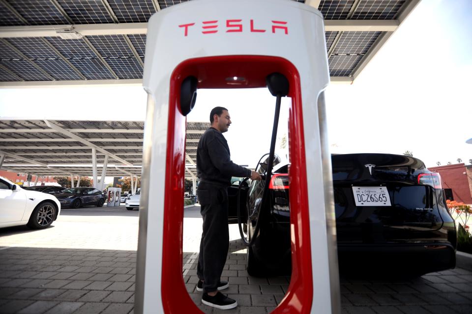 SANTA MONICA, CA - APRIL 17, 2024 - Miguel Castillo plugs in his car to be recharged at a Tesla Supercharger station at the corner of 14th St. and Santa Monica Blvd. in Santa Monica on April 17, 2024. Tesla Inc. is laying off more than 10% of its workforce, Chief Executive Elon Musk wrote in an email to staff. Musk cited job overlap and the need to reduce costs, according to the email sent last Sunday. Bloomberg News estimated that the layoffs would affect more than 14,000 employees. (Genaro Molina/Los Angeles Times via Getty Images)