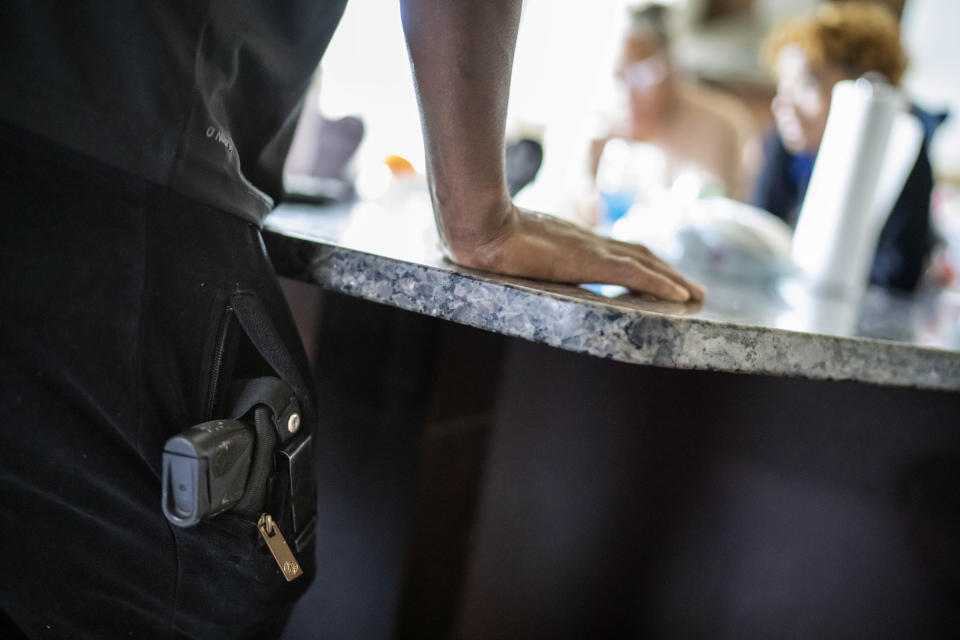 A gun sits in the pocket of Navada Gwynn as he talks with his family in the kitchen of their home in Louisville, Ky., Tuesday, Aug. 29, 2023. Gwynn started carrying a pistol for protection after his daughter was shot and injured, two years after his son was shot and killed. (AP Photo/David Goldman)