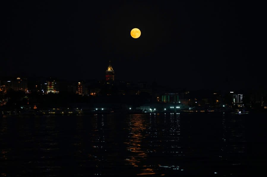 The full moon rises behind the Galata tower in Istanbul, Turkey, Wednesday, Aug. 30, 2023. The cosmic curtain rose Wednesday night with the second full moon of the month, the reason it is considered blue. It is dubbed a supermoon because it is closer to Earth than usual, appearing especially big and bright.(AP Photo/Khalil Hamra)