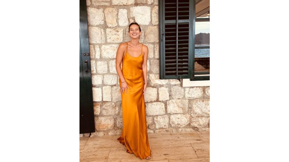 woman standing in front of brick wall in orange dress