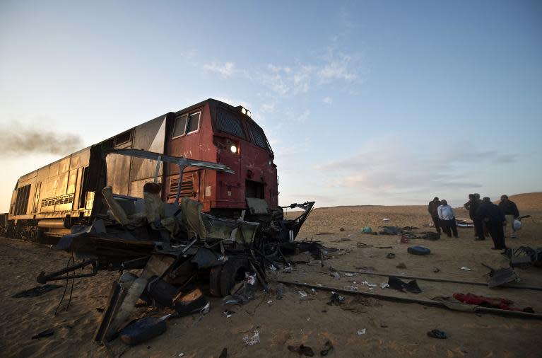 Egyptians gather near the wreckage of a mini-bus at a railway crossing, after a train ploughed into it on November 18, 2013 in Dahshur, killing at least 26 people