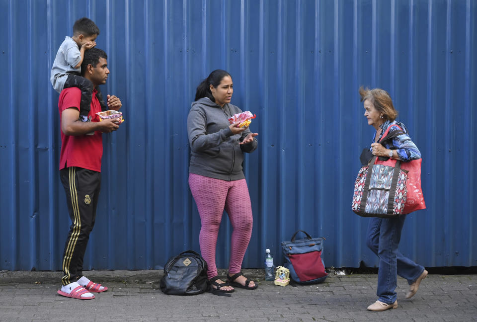 Venezuelan migrants Junior Bucela, left, and his wife Yorlaina Hernandez, center, sell sweets on a street in San Jose, Costra Rica, Tuesday, Dec. 6, 2022. Faced with an overwhelmed asylum system, Costa Rica, one of the world’s great refuges for those fleeing persecution, is tightening its generous policies after President Rodrigo Chaves said the country’s system is being abused by economic migrants. (AP Photo/Carlos Gonzalez)