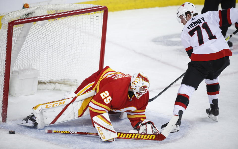 Ottawa Senators' Chris Tierney, right, shoots wide of the net as Calgary Flames goalie Jacob Markstrom covers the post during the second period of an NHL hockey game, in Calgary, Alberta, Sunday, March 7, 2021. (Jeff McIntosh/The Canadian Press via AP)