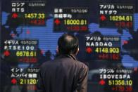 A pedestrian looks at an electronic board displaying various countries' stock market indices outside a brokerage in Tokyo December 24, 2013. REUTERS/Yuya Shino