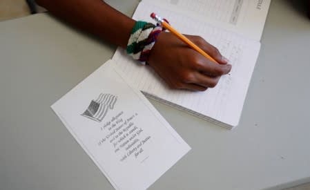 A copy of the Pledge of Allegiance rests next to an immigrant in a writing class the U.S. government's newest holding center for migrant children in Carrizo Springs