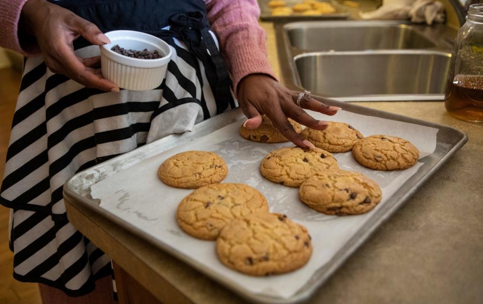 Tiffany Willis, the founder of The Wifestyle Academy, puts extra chocolate chips on a batch of chocolate chip cookies fresh out of the oven inside her home in Southfield on October 12, 2022. 