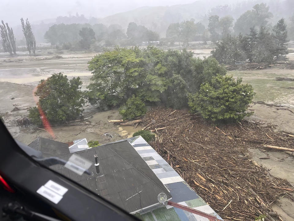 In this image released by the New Zealand Defense Force on Wednesday, Feb. 15, 2023, debris and logs pile up against a building after flooding in the Esk Valley, near Napier, New Zealand. The New Zealand government declared a national state of emergency Tuesday after Cyclone Gabrielle battered the country's north in what officials described as the nation's most severe weather event in years. (New Zealand Defense Force via AP)