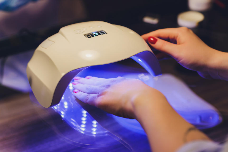 Close-up of beautician applying colorful varnish. Applying nail polish on nails with a brush for applying nail polish on fingers. Manicure nail applicator in a beauty salon. In a beauty salon varnish