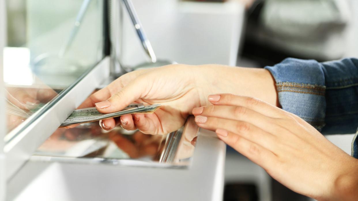 Hand with money in cash department window.