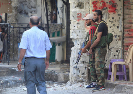 Members of the joint Palestinian security force stand in front of a bullet-riddled wall inside the Ain el-Hilweh refugee camp near Sidon, southern Lebanon, August 18, 2017. REUTERS/Ali Hashisho