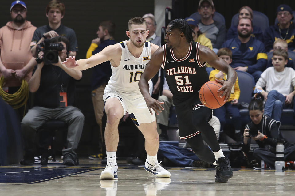Oklahoma State guard John-Michael Wright (51) is defended by West Virginia guard Erik Stevenson (10) during the second half of an NCAA college basketball game on Monday, Feb. 20, 2023, in Morgantown, W.Va. (AP Photo/Kathleen Batten)
