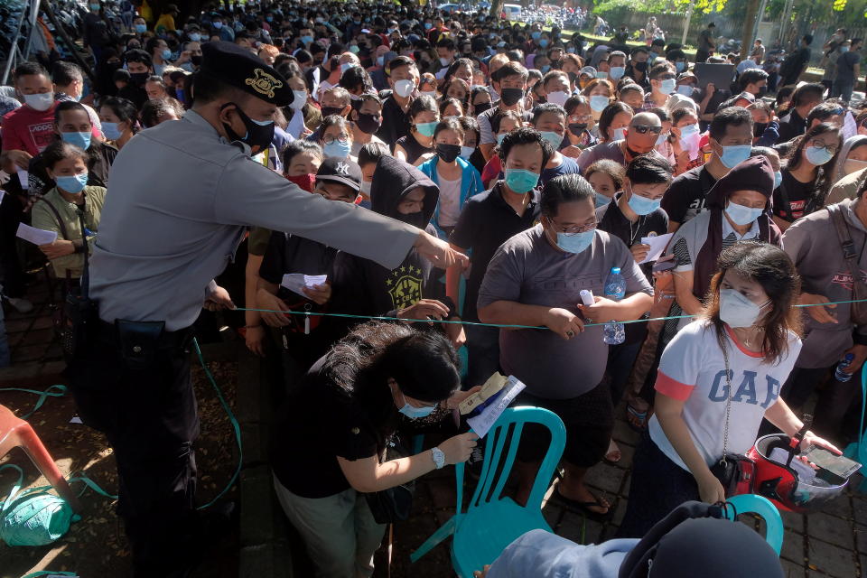 A police officer controls people as they queue for coronavirus disease (COVID-19) vaccine during a mass vaccination in Denpasar, Bali, Indonesia, June 26, 2021, in this photo taken by Antara Foto. Antara Foto/Nyoman Hendra Wibowo/ via REUTERS  ATTENTION EDITORS - THIS IMAGE WAS PROVIDED BY A THIRD PARTY. MANDATORY CREDIT. INDONESIA OUT.