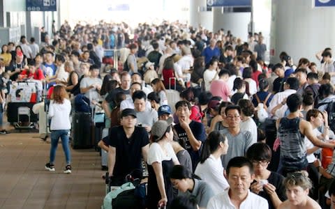 Stranded passengers queue up in lines to wait for special buses at Kansai International Airport  - Credit: AP