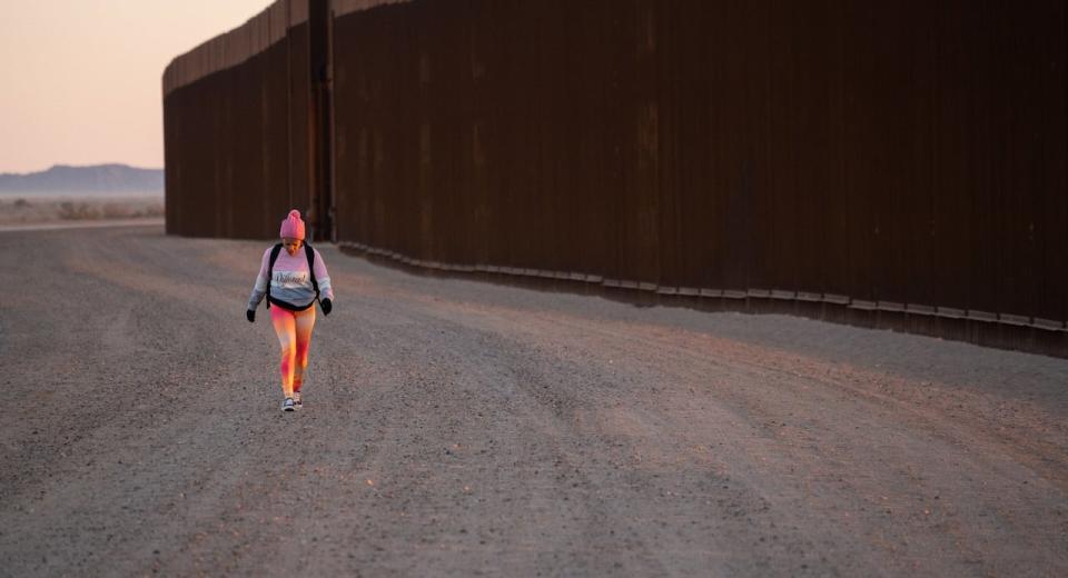 Under a golden sunrise, a migrant walks into the U.S. along a border wall in San Luis, Ariz., just outside Yuma: 