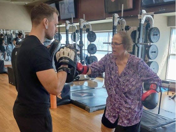 A personal trainer sparring with his client at a gym