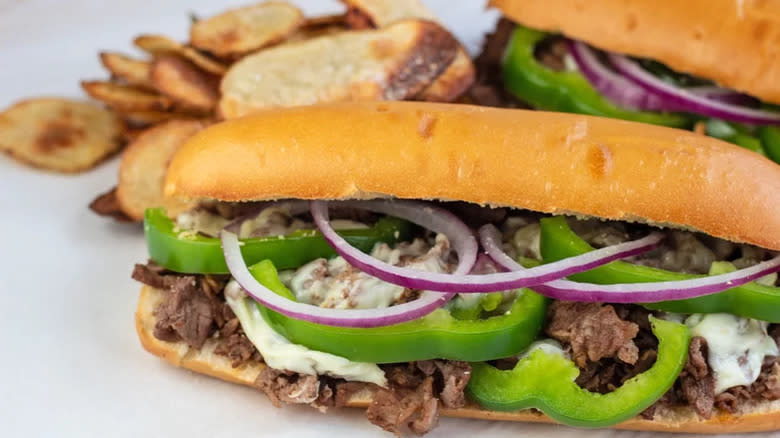 Sub steak sandwiches with green bell pepper and red onion slices
