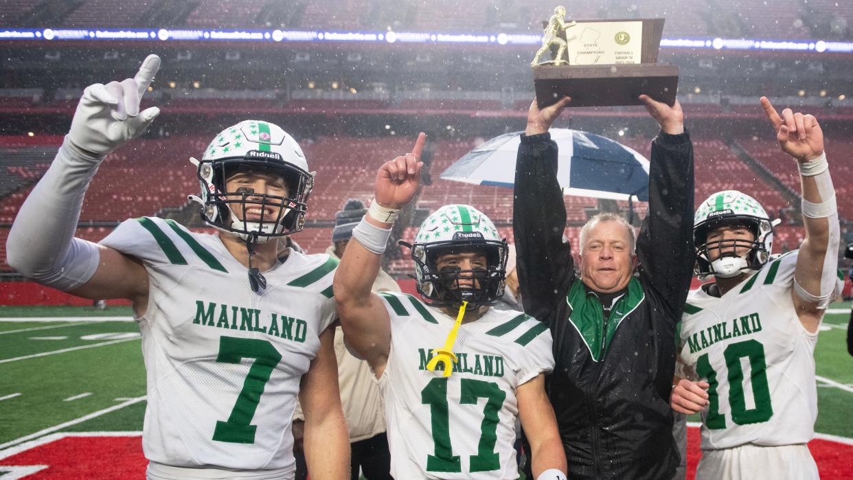 Mainland High School's head football coach Chuck Smith hoists the trophy and celebrates with Mainland players (from left); Javien Swain, Stephen Ordille and Cohen Cook
after Mainland defeated Ramapo, 56-0, in the Group 4 state championship football game played at Rutgers University in Piscataway on Sunday, November 26, 2023.