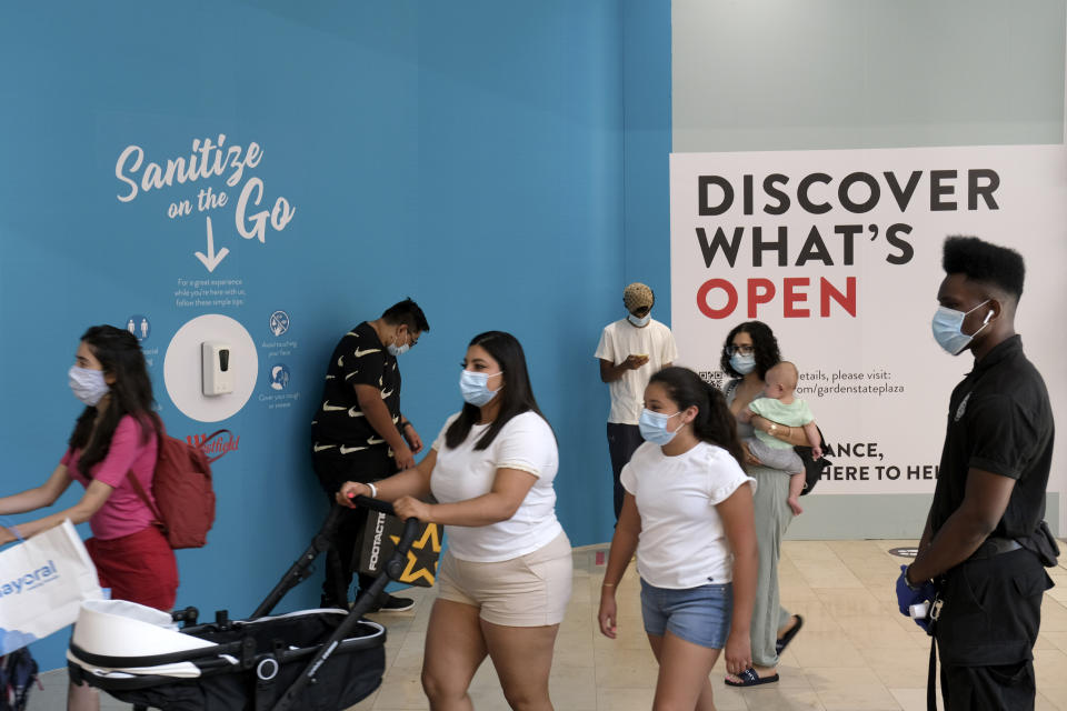 FILE - In this Monday, June 29, 2020, file photo, shoppers walk around Garden State Plaza in Paramus, N.J., as New Jersey's indoor shopping malls reopened Monday from their COVID-19 pause. U.S. employers likely rehired several million more workers in June, thereby reducing a Depression-level unemployment rate, but the most up-to-date data suggests that a resurgent coronavirus will limit further gains. (AP Photo/Seth Wenig, File)