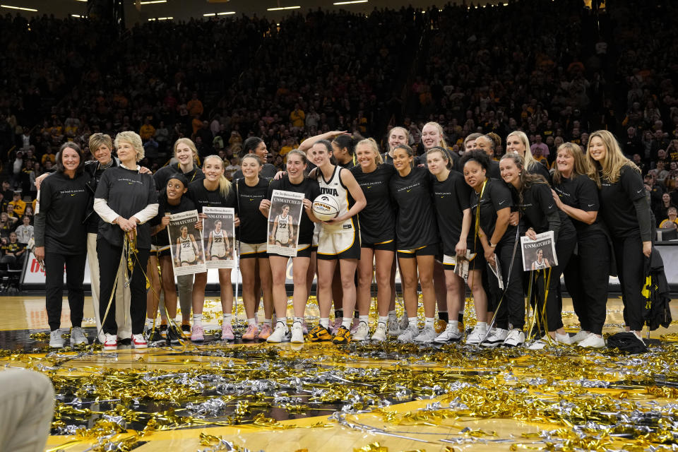 Iowa guard Caitlin Clark (22) is presented with a commemorative basketball after the team's NCAA college basketball game against Michigan on Thursday, Feb. 15, 2024, in Iowa City, Iowa. Clark set a new NCAA women's career scoring record. (AP Photo/Matthew Putney)