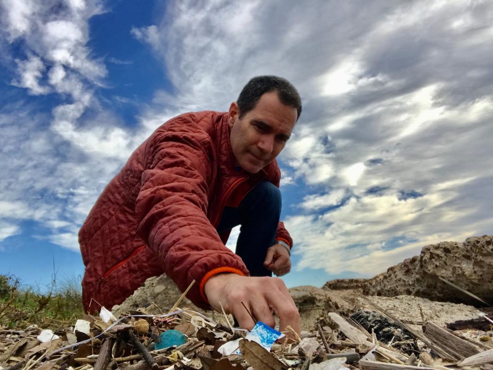 Jace Tunnell, director of the Mission-Aransas National Estuarine Research Reserve at the University of Texas Marine Science Institute, sifts through trash on the beach on Mustang Island in Texas.