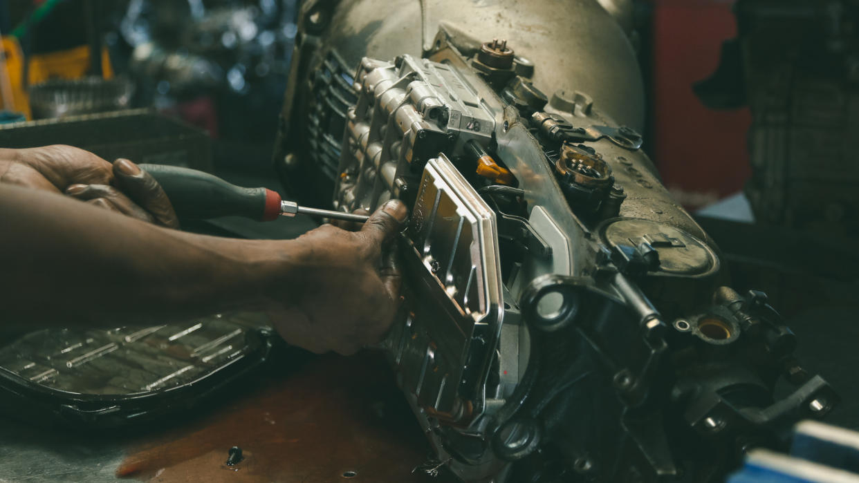 Auto shop owner taking apart his car transmission.