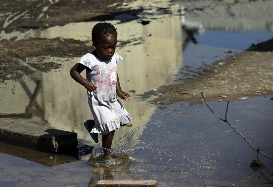 A young girl walks into the water outside a school setup as a displacement centre at Inhamizua, outside of Beira, Mozambique, Tuesday, March 26, 2019. Cyclone-ravaged Mozambique faces a "second disaster" from cholera and other diseases, the World Health Organization warned on Tuesday, while relief operations pressed into rural areas where an unknown number of people remain without aid more than 10 days after the storm. (AP Photo/Themba Hadebe)