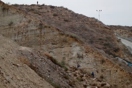 Migrants, part of a caravan of thousands from Central America trying to reach the United States, walk close to the border wall as they try to cross from Mexico to the U.S., while a U.S. Customs and Border Protection (CBP) official stands guard at the top of a hill, as seen from Tijuana, Mexico, December 9, 2018. REUTERS/Carlos Garcia Rawlins