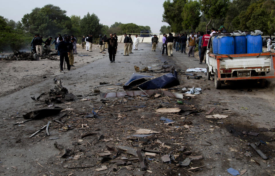 Pakistani security officials and journalists gather at the site of a bombing in Karachi, Pakistan, Thursday, Feb. 13, 2014. A bomb attack killed at least several police officers and wounded dozens others in Pakistan's southern city of Karachi on Thursday. A van exploded after hitting a bus the officers boarded moments after it had left a training school in what appeared to be a suicide attack, said police officer Rao Anwaar. (AP Photo/Shakil Adil)