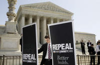 A campaign aide for Republican presidential candidate Rick Santorum, sets up signs in front of the Supreme Court.