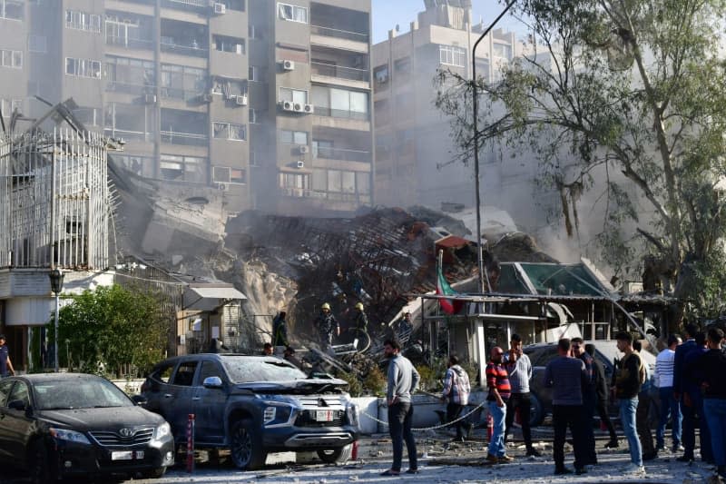 A photo released by the official Syrian Arab news agency (SANA) on 01 April shows people gathering around an Iranian diplomatic destroyed building after a suspected Israeli airstrike. -/SANA/dpa