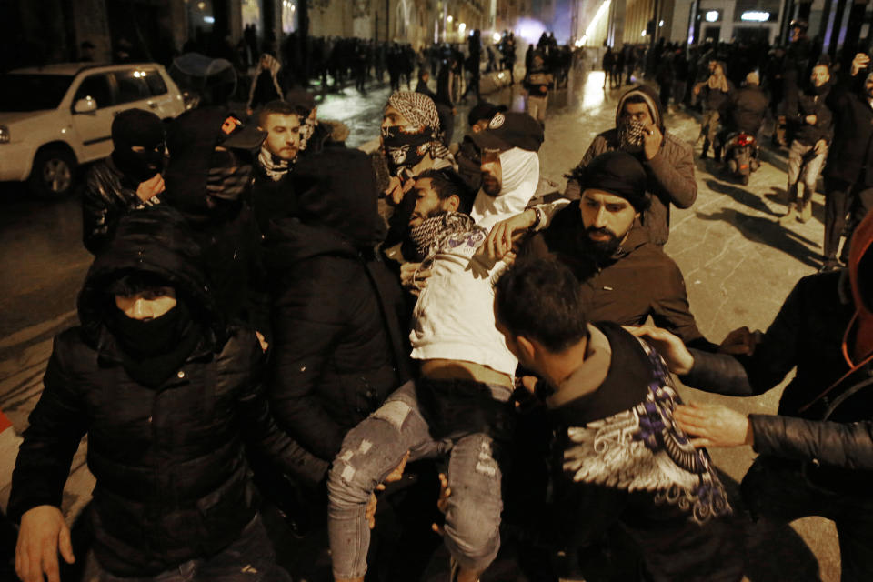 Anti-government protesters carry an injured person during ongoing protests in Beirut, Lebanon, Wednesday, Jan. 22, 2020. Lebanon's new government held its first meeting Wednesday, a day after it was formed following a three-month political vacuum, with the prime minister saying his Cabinet will adopt financial and economic methods different than those of previous governments. (AP Photo/Bilal Hussein)