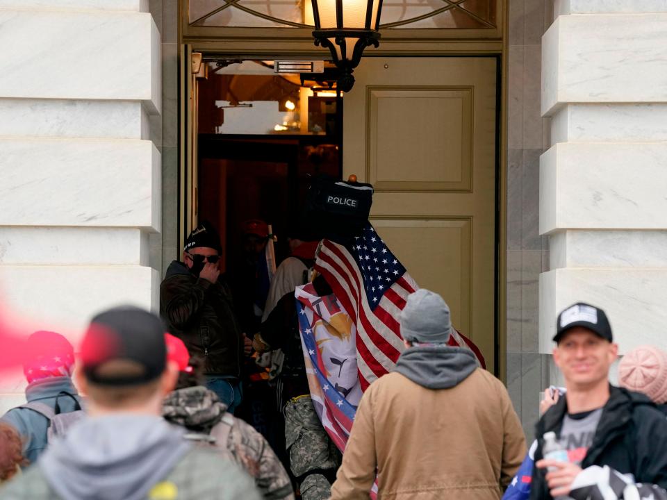Supporters of then-US President Donald Trump storm through the door at the US Capitol