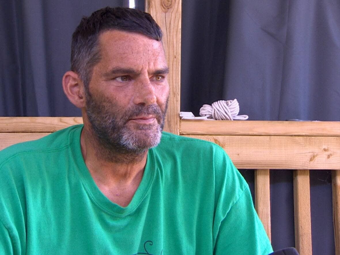 Stefan Aulenbach sits on the deck of the RV that he lives in with his family.  (Brian MacKay/CBC - image credit)