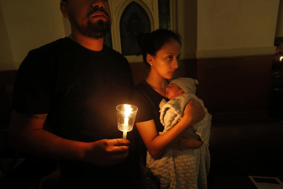 Neftali Davila prays with his wife, Mayte Davila, as she holds their child Mateo Davila during a prayer vigil