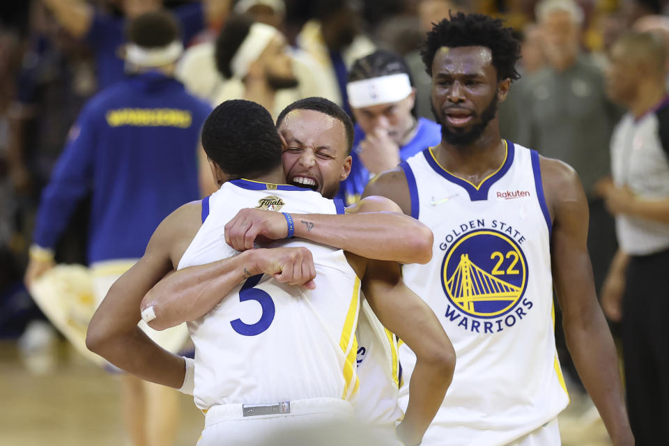CORRECTS TO GAME 2 INSTEAD OF GAME 1 - Golden State Warriors guard Jordan Poole, left, celebrates with guard Stephen Curry, middle, and forward Andrew Wiggins (22) after scoring against the Boston Celtics during the second half of Game 2 of basketball's NBA Finals in San Francisco, Sunday, June 5, 2022. (AP Photo/Jed Jacobsohn)