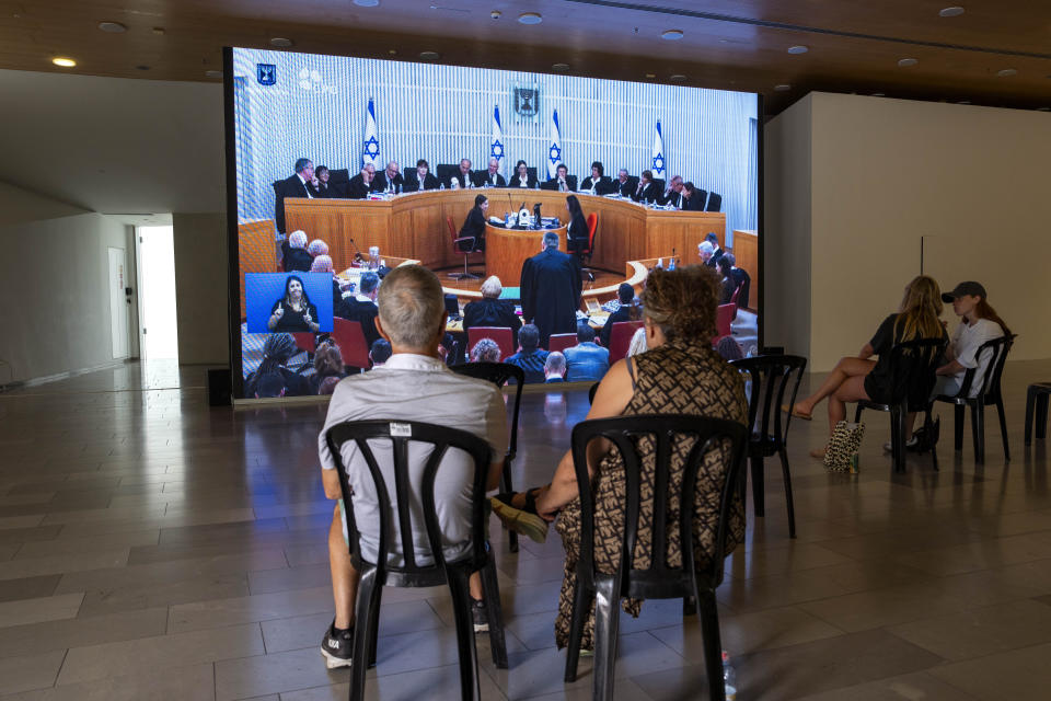 Israelis watch a live broadcast of Israel's Supreme Court justices as they hear deliberations in the first case challenging Prime Minister Benjamin Netanyahu's judicial overhaul in Tel Aviv, Israel, Tuesday, Sept. 12, 2023. The contentious plan has triggered months of mass protests and bitterly divided the country. (AP Photo/Oded Balilty)