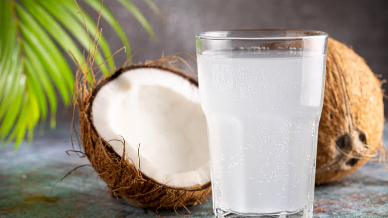 glass of coconut water beside coconuts