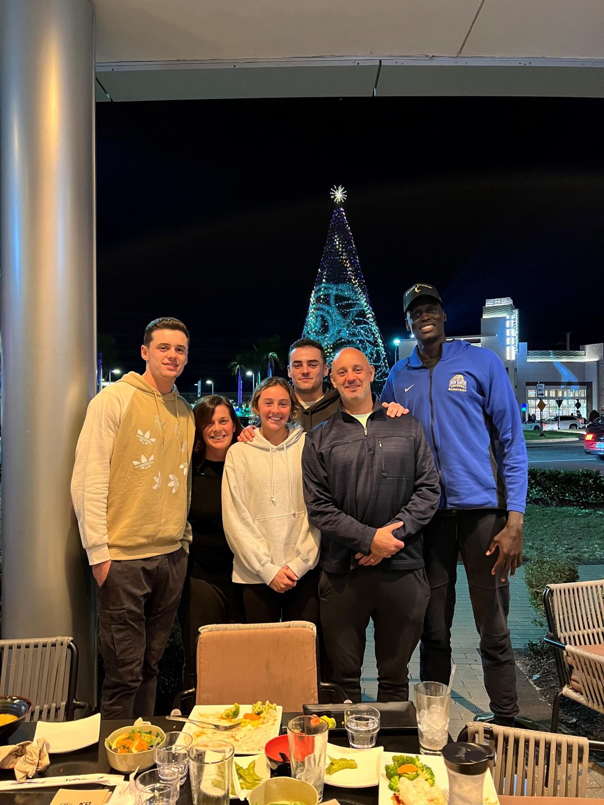 The Peek family poses while out for dinner in 2023. From left: Sam, Dana, Kate, Hayden and Ryan Peek, and Majur Majak, a Sudanese native whom the Poughkeepsie family hosts.