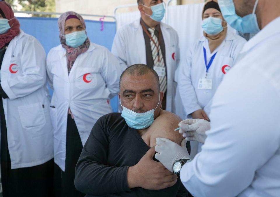 CISJORDANIA: Un médico administra una vacuna Moderna COVID-19 a un compañero médico durante una campaña para vacunar a los trabajadores médicos de primera línea, en el Ministerio de Salud, en la ciudad de Belén en Cisjordania, el 3 de febrero de 2021.