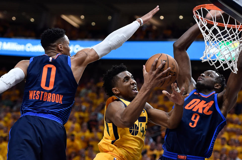 Donovan Mitchell slices between the defense of Russell Westbrook (left) and Jerami Grant as he heads to the basket during the Jazz’s Game 6 win over the Thunder. (Getty)