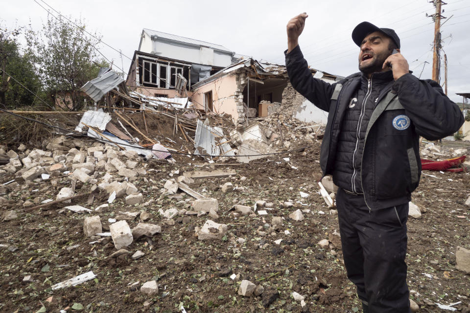 A man speaks phone near a house destroyed by shelling by Azerbaijan's artillery during a military conflict in Stepanakert, self-proclaimed Republic of Nagorno-Karabakh, Thursday, Oct. 8, 2020. Armenia accused Azerbaijan of firing missiles into the capital of the separatist territory of Nagorno-Karabakh, while Azerbaijan said several of its towns and its second-largest city were attacked. (AP Photo)