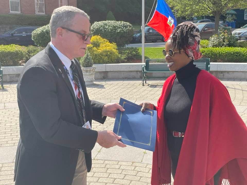 Norwich Mayor Peter Nystrom presents Greeneville Neighborhood Committee Vice President Cynthia Jean-Mary with a proclamation recognizing the Haitian community in Norwich during the Haitian Flag Raising on May 18.