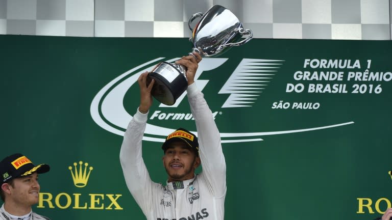 Mercedes AMG Petronas F1 Team's British driver Lewis Hamilton celebrates with the trophy on the podium after winning the Brazilian Grand Prix at the Interlagos circuit in Sao Paulo, Brazil, on November 13, 2016