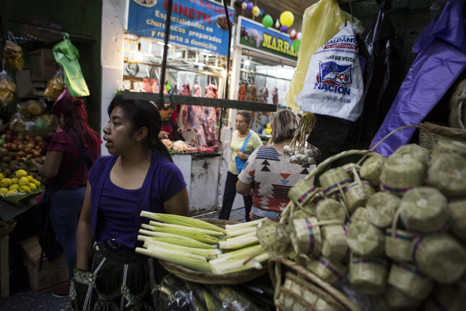 Plastic bags with the logo of the ruling party, FCN Nacion, hang at a handcrafts stand inside the central market in Guatemala City, Saturday, June 15, 2019. As Guatemala goes to the polls on Sunday, they favor former first lady Sandra Torres of the National Unity and Hope party to finish first, but with 19 candidates in the race it is unlikely she will win the absolute majority necessary to avoid a runoff. (AP Photo/Oliver de Ros)